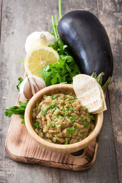 Smoky aubergine crush topped with herbs and olive oil, featuring charred roasted aubergine blended into a rich, creamy dip.