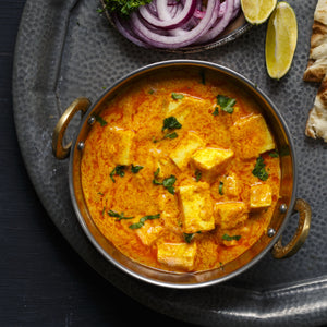 Paneer makhani with soft paneer cubes in a rich, creamy tomato butter sauce, garnished with fresh herbs and spices.