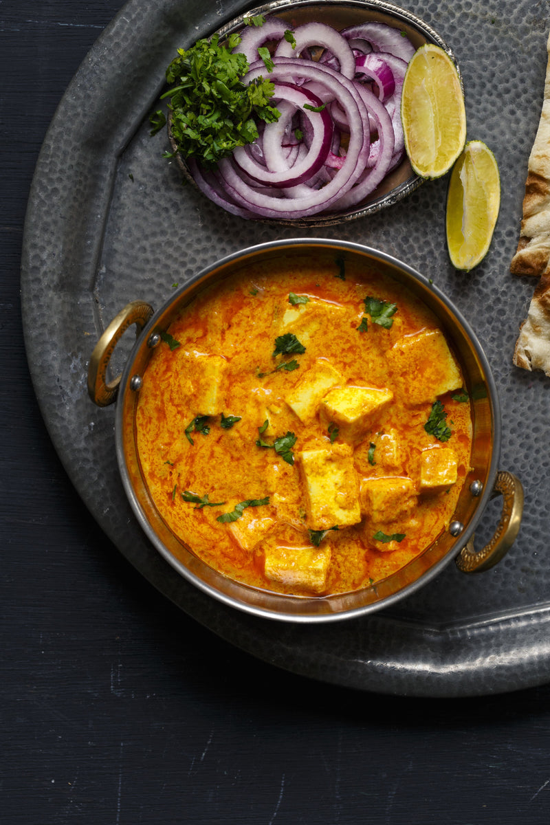 Paneer makhani with soft paneer cubes in a rich, creamy tomato butter sauce, garnished with fresh herbs and spices.