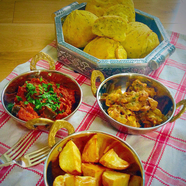 Aubergine madras served with onion bhajis, potatoes, and spiced bread rolls