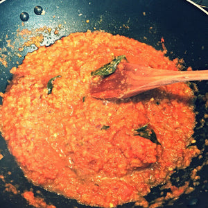Homemade curry paste cooking in a pan with curry leaves