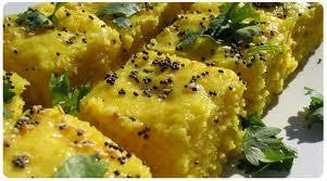 Soft, fluffy yellow dhokla topped with mustard seeds and fresh coriander, served in bite-sized squares.