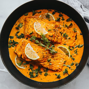 Salmon curry with tender salmon fillets simmered in a spiced coconut or tomato-based sauce, garnished with herbs.