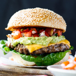 Mexican beef burger with a juicy beef patty, spicy seasoning, fresh salad, and melted cheese in a soft bun.