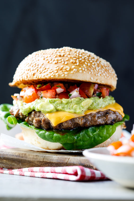 Mexican beef burger with a juicy beef patty, spicy seasoning, fresh salad, and melted cheese in a soft bun.