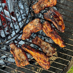 BBQ Chinese pork belly with tender slices of pork coated in a glossy barbecue glaze, garnished with herbs.