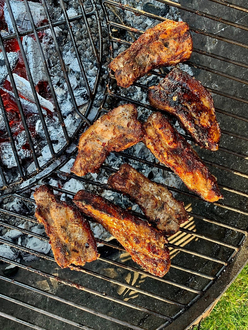 BBQ Chinese pork belly with tender slices of pork coated in a glossy barbecue glaze, garnished with herbs.