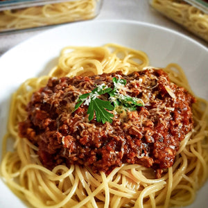 Spicy Spaghetti Bolognese served in a white bowl with a fresh coriander garnish