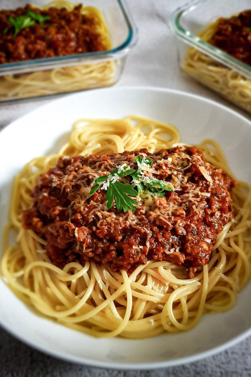 Spicy Spaghetti Bolognese served in a white bowl with a fresh coriander garnish