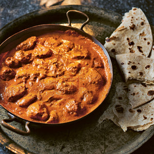 A bowl of Ultimate (and Speedy) Butter Chicken served with naan