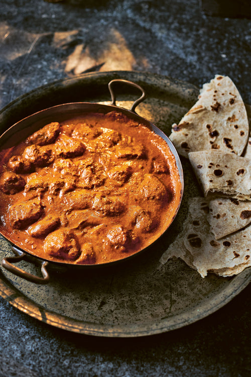 A bowl of Ultimate (and Speedy) Butter Chicken served with naan