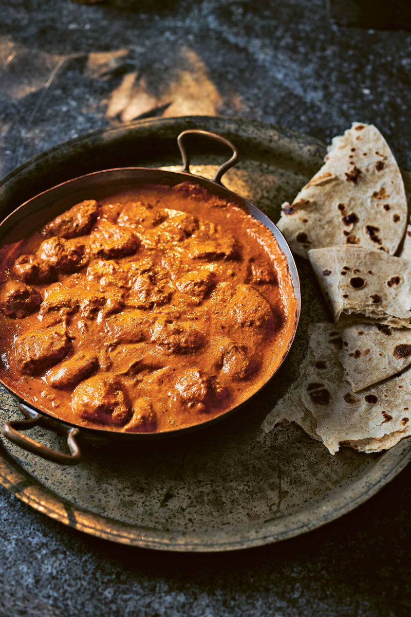 A bowl of Ultimate (and Speedy) Butter Chicken served with naan