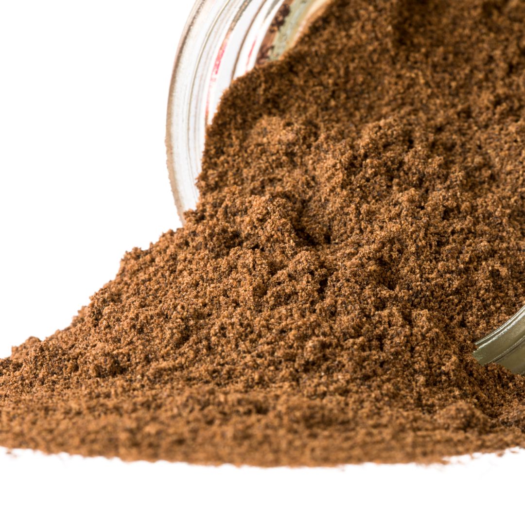 Close-up of ground Spice Kitchen allspice spilling from a jar onto a white background