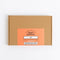 A square brown kraft cardboard box with a peach-orange front label reading 'Spice Kitchen' and 'GIN', photographed on a clean white background.