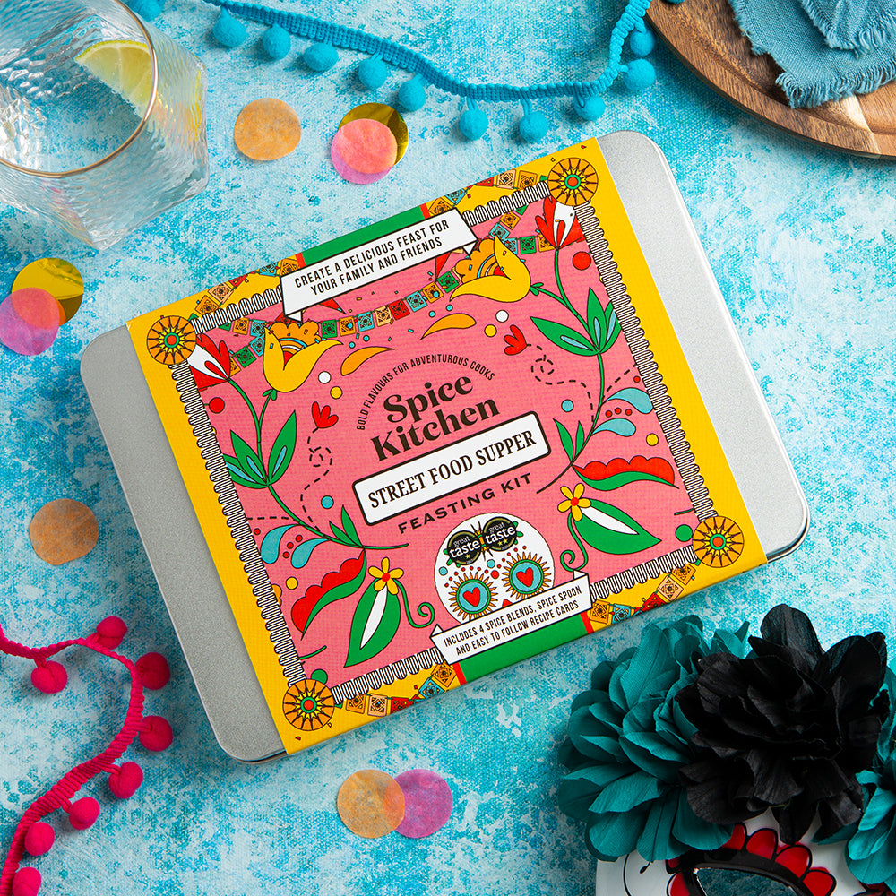 Spice Kitchen Street Food Supper kit on a colorful background with flowers and a glass of lemon flavoured water.