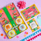 Colorful Spice Kitchen Feasting Kit product set with tins, packaging, recipe cards, a shopping list and a pink bow on a purple background.