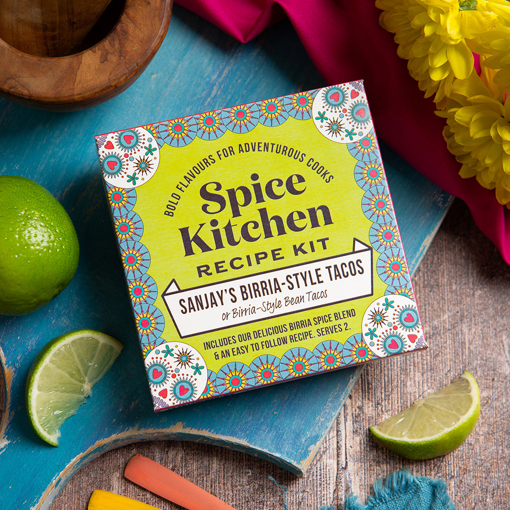 Sanjay's Birria Taco Recipe Kit on a wooden board with decorative kitchen items