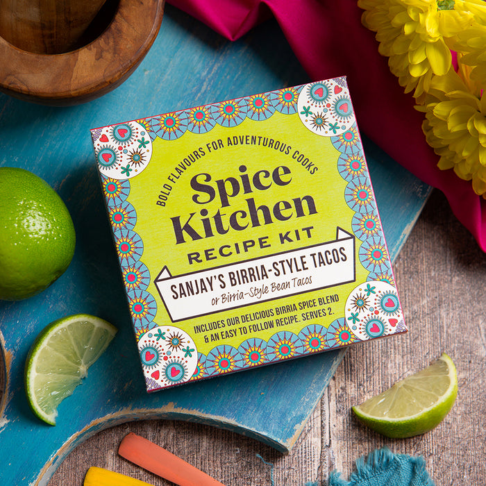 Sanjay's Birria Taco Recipe Kit on a wooden board with decorative kitchen items