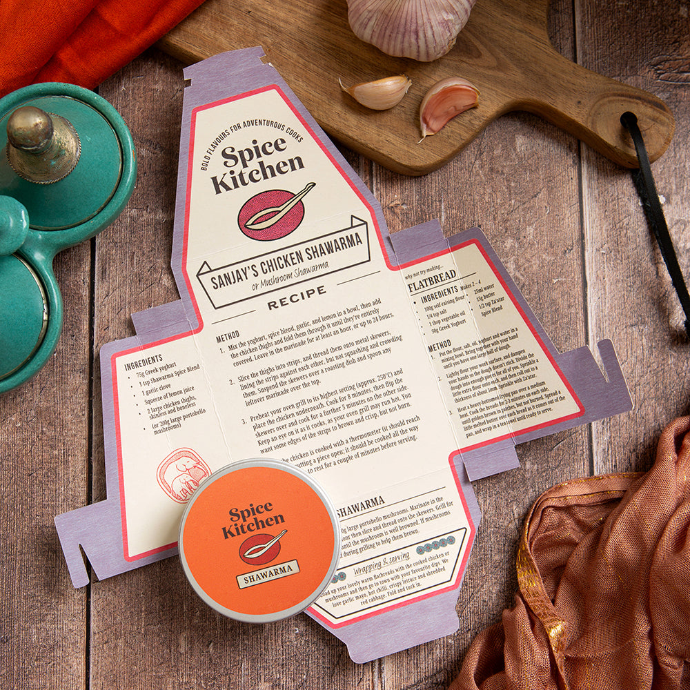 Spice Kitchen recipe card for Sanjay's Chicken Shawarma on a wooden surface with kitchen items.