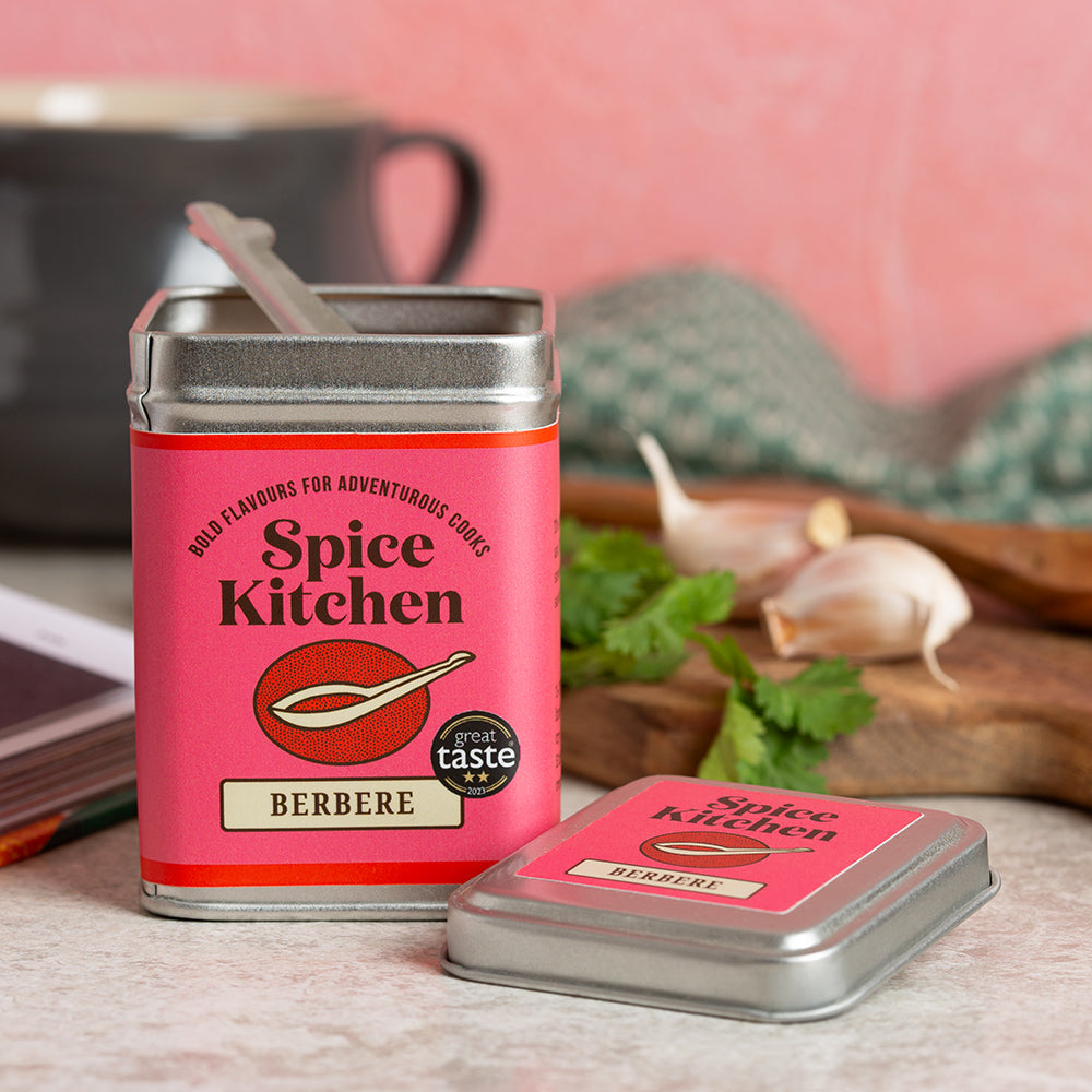 Spice Kitchen Berbere spice tin with a spoon on a kitchen counter.