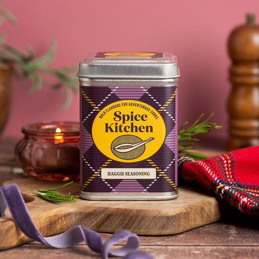 Spice Kitchen's Haggis Seasoning on a colourful background with tartan fabric, a purple ribbon on a chopping board 