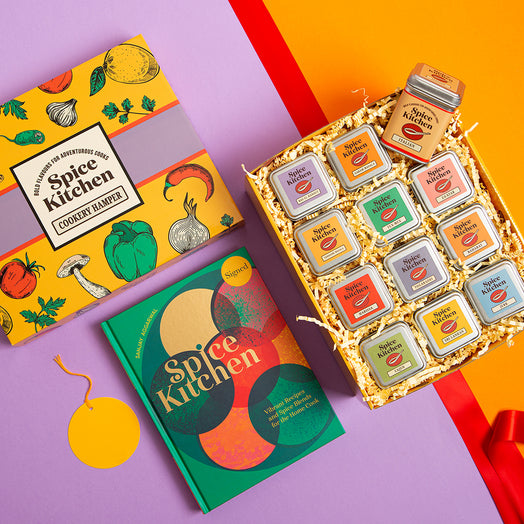 Spice Kitchen Signature Spice Blend & Cookery Book Gifting Hamper set with colourful tins and Sanjay Aggarwal's cookery book on a purple background