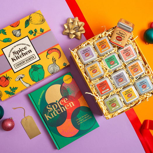 Spice Kitchen Signature Spice Blend & Cookery Book Gifting Hamper set with colourful tins and Sanjay Aggarwal's cookery book on a purple background