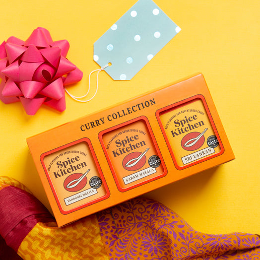Spice Kitchen Curry Collection packaging with a pink bow on a yellow background