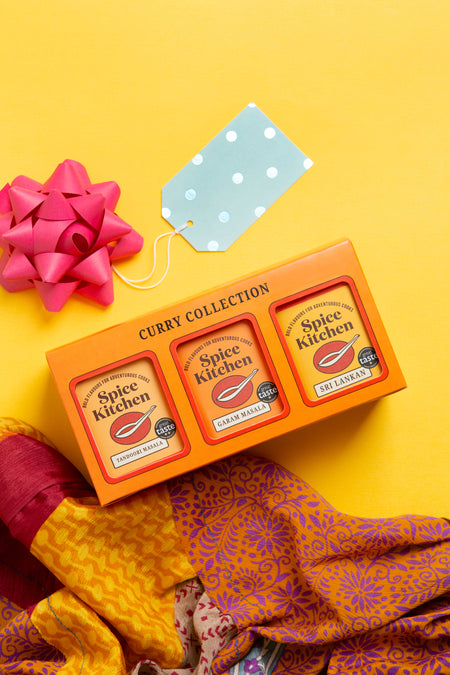 Spice Kitchen Curry Collection packaging with a pink bow on a yellow background