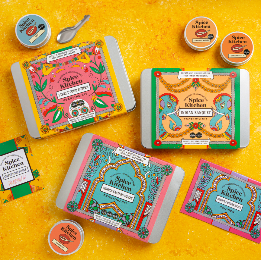 Spice Kitchen Feasting Kit Range on a yellow background with spice spoon, round pots of spice blends, a recipe card and a shopping list