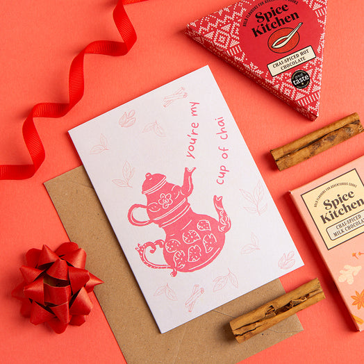Spice Kitchen product packaging with a card and cinnamon sticks on a red background ' text says 'You're my cup of chai'