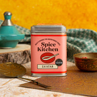 Spice Kitchen Za'atar spice tin on a rustic wooden surface with kitchen items in the background.