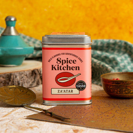 Spice Kitchen Za'atar spice tin on a rustic wooden surface with kitchen items in the background.