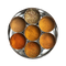 A top-down view of a round silver metal spice tray with seven small inner tins filled with different ground spices in warm brown, orange, and yellow tones.